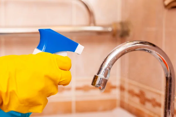 Mano en un guante de goma amarillo desinfecta el grifo de agua en el baño —  Fotos de Stock