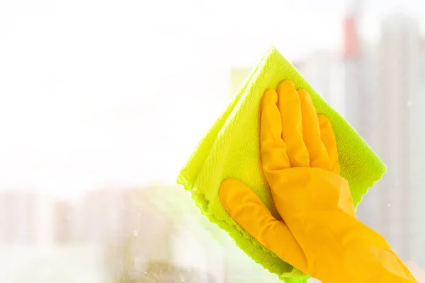 Mano en un guante de goma amarillo limpia la ventana de cerca —  Fotos de Stock