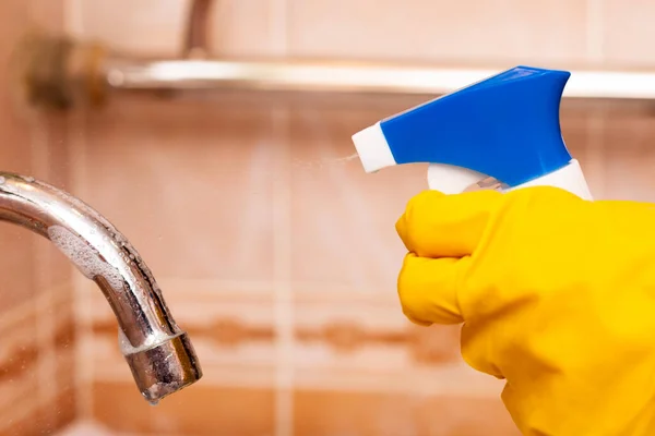 Mano en un guante de goma amarillo desinfecta el grifo de agua en el baño — Foto de Stock