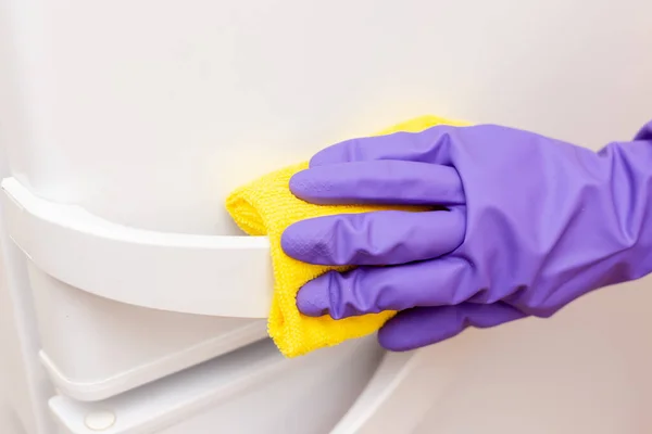 La mano de las mujeres limpia la puerta blanca del refrigerador — Foto de Stock