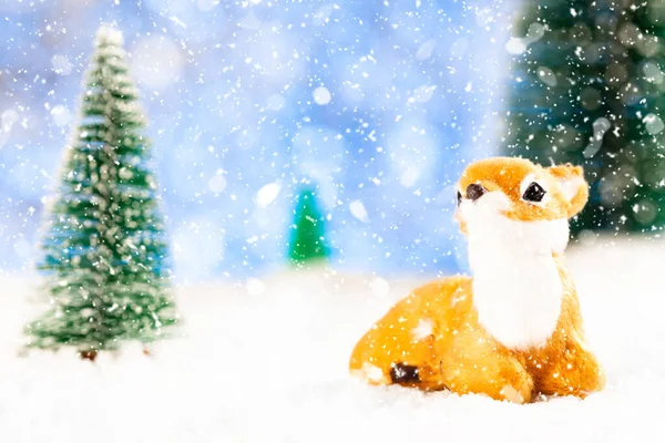 Το μικρό ελάφι κάθεται στο χιόνι. Γύρω από έλατα παιχνιδιών. Νέο έτος ευχετήρια κάρτα — Φωτογραφία Αρχείου
