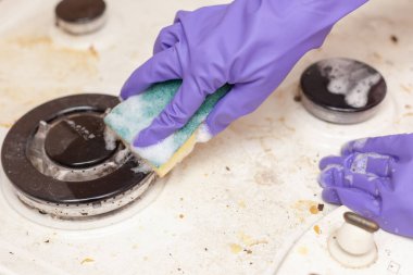 Eldivendeki kadın eli sobayı yıkar.