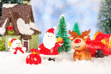 Yeni yıl tebrik kartı. Oyuncak bir Noel Baba Noel kızağının üstünde duruyor. Yakınlarda bir oyuncak ev, bir kardan adam, bir geyik var. Her yer kar ve oyuncak kaynıyor.