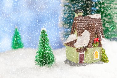 Noel tebrik kartı. Kardaki çam ağaçlarının arasında bir oyuncak ev. Boşluğu kopyala, kavram