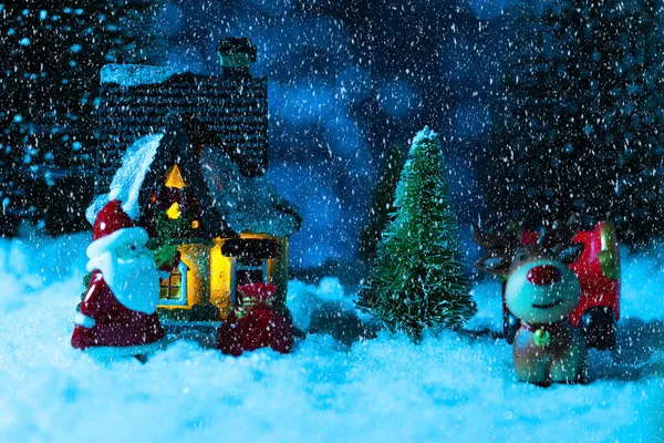 Kerstman op een slee in de buurt van het dorp huis, het sneeuwt, nacht. Nieuwjaarskaart, concept — Stockfoto