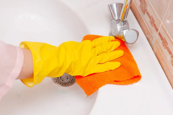 Mano en un guante de goma amarillo limpia el lavabo en el baño — Foto de Stock