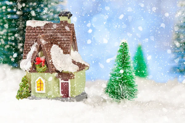 Weihnachtsgrußkarte vorhanden. Ein Spielzeughaus inmitten von Kiefern im Schnee. Kopierraum, Konzept — Stockfoto