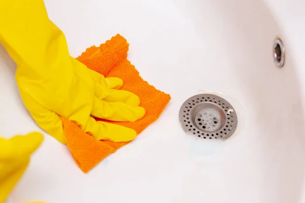Рука в жовтій гумовій рукавичці протирає раковину у ванній кімнаті — стокове фото