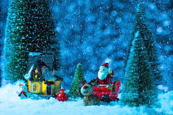 Ο Άγιος Βασίλης σε ένα έλκηθρο κοντά στο σπίτι του χωριού, χιονίζει, νύχτα. Νέο έτος ευχετήρια κάρτα, έννοια — Φωτογραφία Αρχείου