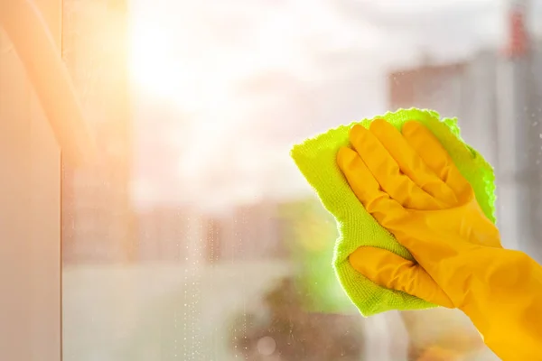 Mano en un guante de goma amarillo limpia la ventana de cerca — Foto de Stock