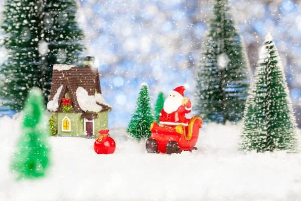 Παιχνίδι Άγιος Βασίλης και έλκηθρο στο χιόνι, τεχνητά έλατα γύρω, χριστουγεννιάτικη ευχετήρια κάρτα — Φωτογραφία Αρχείου