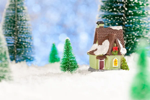 Cartão de Natal. Uma casa de brinquedo entre pinheiros de brinquedo na neve. Espaço de cópia, conceito — Fotografia de Stock