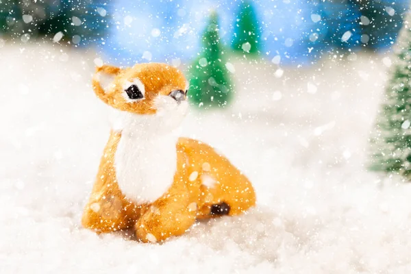 Μικρό ελάφι παιχνίδι κάθεται στο χιόνι στο δάσος, ευχετήρια κάρτα, αντίγραφο χώρο — Φωτογραφία Αρχείου