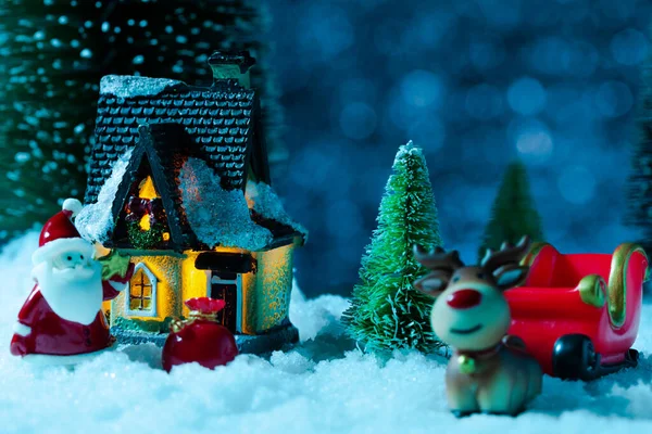 Ο Άγιος Βασίλης σε ένα έλκηθρο κοντά στο σπίτι του χωριού, χιονίζει, νύχτα. Νέο έτος ευχετήρια κάρτα, έννοια — Φωτογραφία Αρχείου