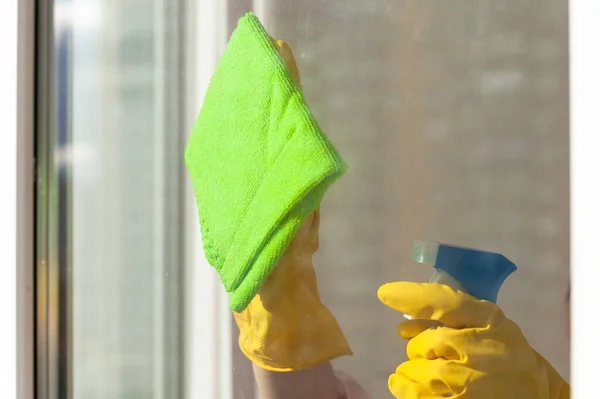 Hand in a yellow rubber glove wipes the window close-up — Stock Photo, Image