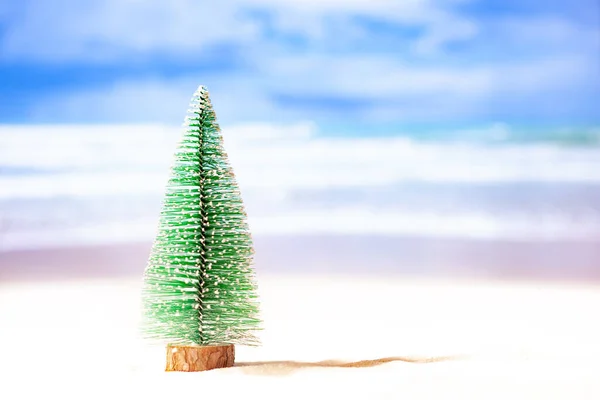 Toy christmas tree on the beach with ocean background — Stock Photo, Image