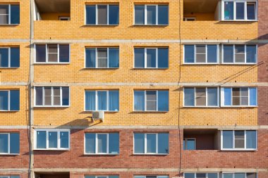 Pencereleri ve balkonları olan tuğladan bir apartmanın ön cephesi