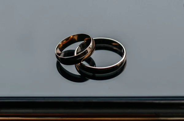 ブラックガラスに結婚指輪が2つ — ストック写真