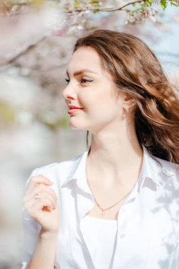 Sakura ağaçlarının yanında beyaz gömlekli bir kız. Sakura çiçekleri. Bahar.