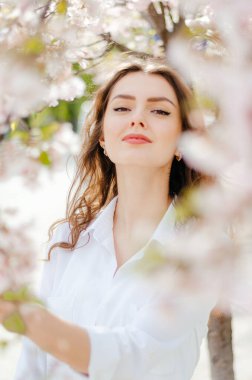 Sakura ağaçlarının yanında beyaz gömlekli bir kız. Sakura çiçekleri. Bahar.