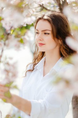 Sakura ağaçlarının yanında beyaz gömlekli bir kız. Sakura çiçekleri. Bahar.