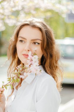 Baharda elinde sakura dalı olan beyaz gömlekli bir kız.