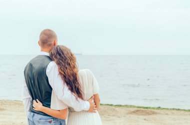 Kadın ve erkek kıyıda durup denize bakıyorlar.