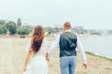 Erkek ve kadın düğün kıyafetleriyle sahilde koşuyorlar.