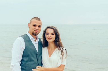 Karı koca deniz kenarında kucaklaşıyorlar.