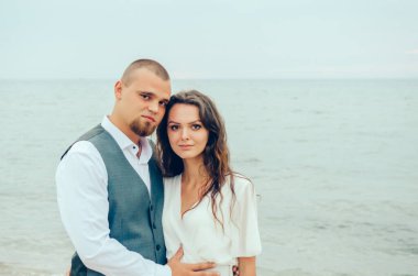 Karı koca deniz kenarında kucaklaşıyorlar.