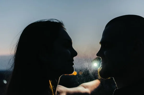 Silhouette of man and woman at night with water splashes