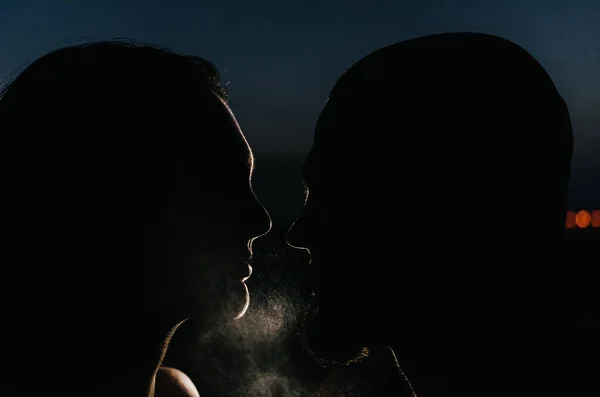 Silhouette of man and woman at night with water splashes