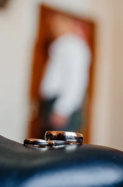 wedding rings on a black stand with a man on the background