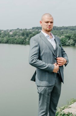 Doğanın arka planında gri takım elbiseli bir adam.