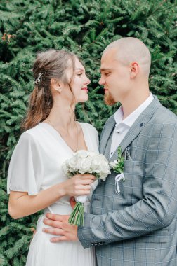 Gelin ve damat yeşil yaprakların yanında sarılıyorlar.