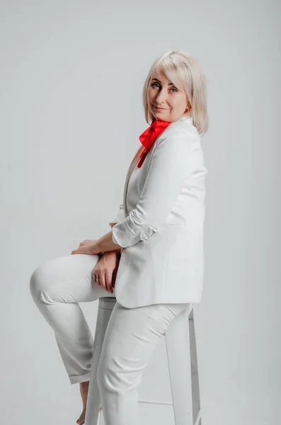 a woman in a white suit with a red scarf on a white background