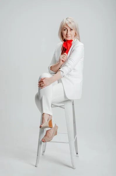 a woman in a white suit with a red scarf on a white background