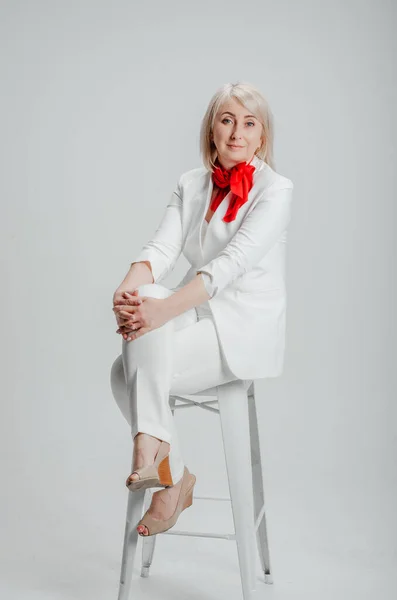 a woman in a white suit with a red scarf on a white background