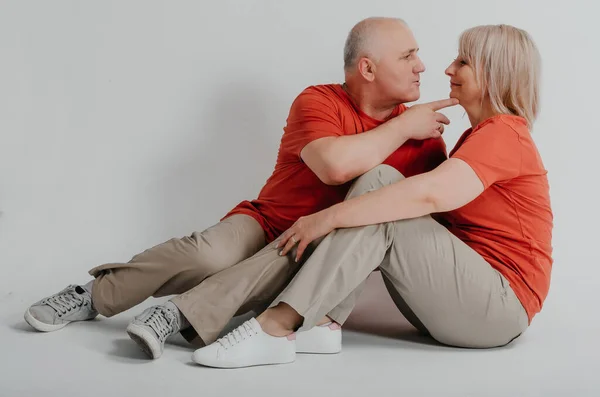 couple in love in orange t-shirts laughing and hugging on a white background