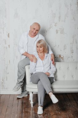 Bir adam ve karısı kanepede beyaz gömlekli.