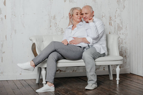 a man and his wife in white shirts on the couch