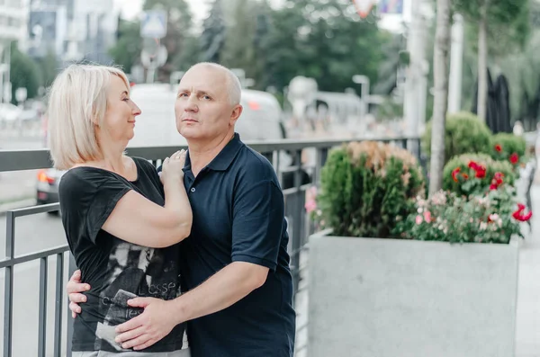 a man and his wife in black T-shirts are hugging in the city