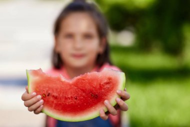 Çocuk kız güneşli bir günde karpuz yiyor.