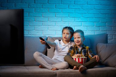 Uzaktan kumandalı iki çocuk televizyon izliyor.