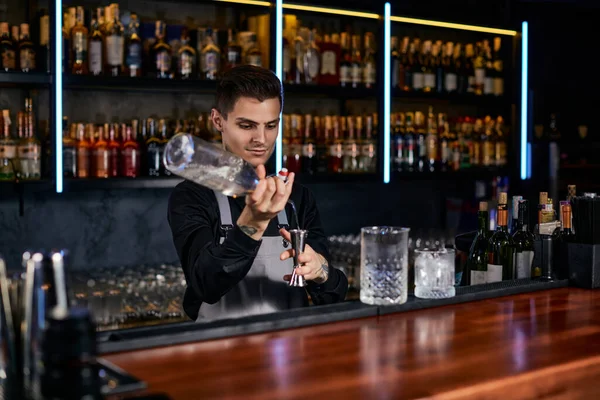 Barman v zástěře přidává do skla přísadu — Stock fotografie