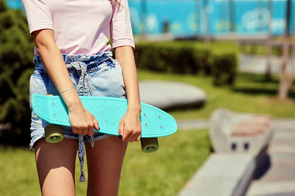 Mladá dívka v kraťasech drží modrý skateboard — Stock fotografie