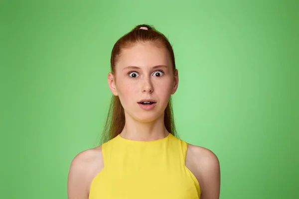 Verrast tienermeisje op groene achtergrond. Menselijke emoties — Stockfoto