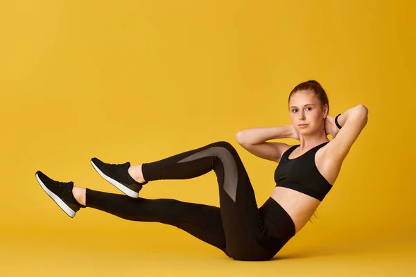 Flicka i svart sportkläder gör v-ups abs träning — Stockfoto
