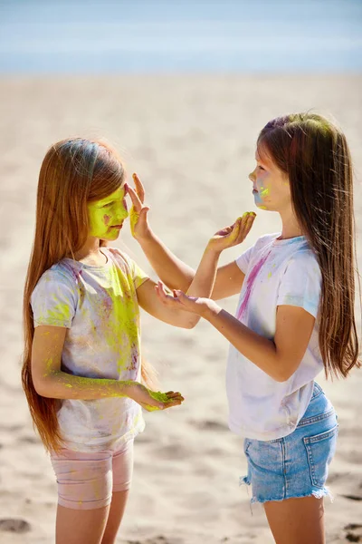 Kind meisjes besmeurd met gekleurd poeder vieren holi festival. — Stockfoto
