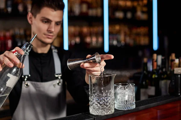 Bartender em avental adiciona ingrediente ao vidro — Fotografia de Stock